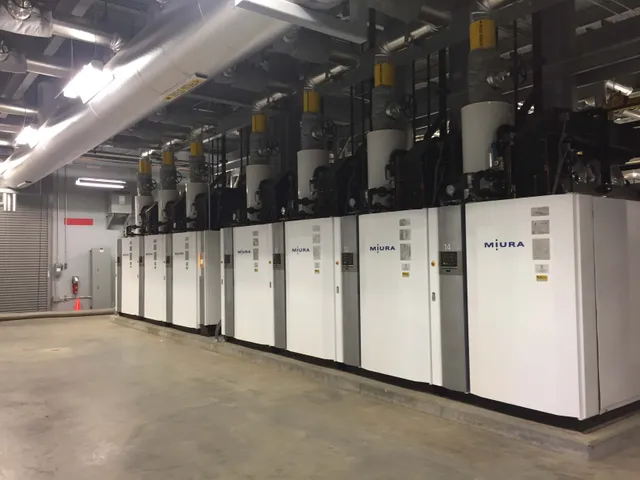 Row of Miura modular steam boilers with insulated overhead steam headers in a commercial boiler room